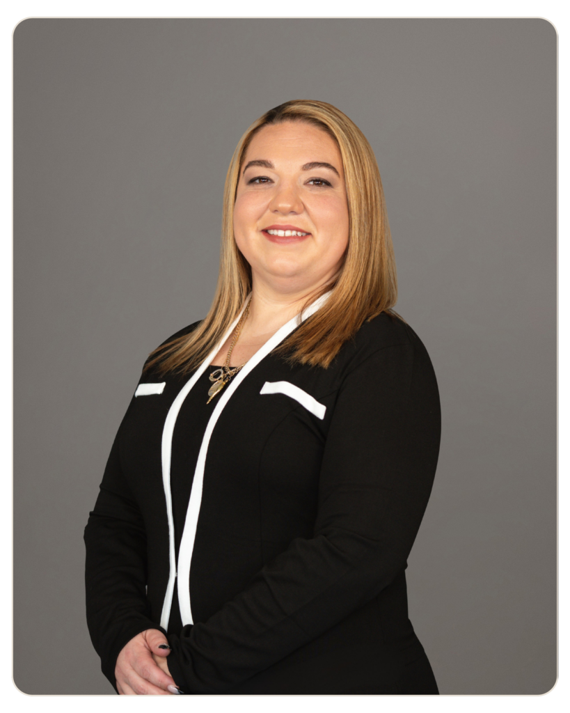 Frances Donato, RN Portrait of a smiling woman with blonde hair in a black blazer with white trim, against a gray studio background.